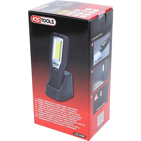 Een zwarte werkplaatslamp staat in zijn oplaadstation voor een rode doos. Op de doos staat "KS TOOLS".
